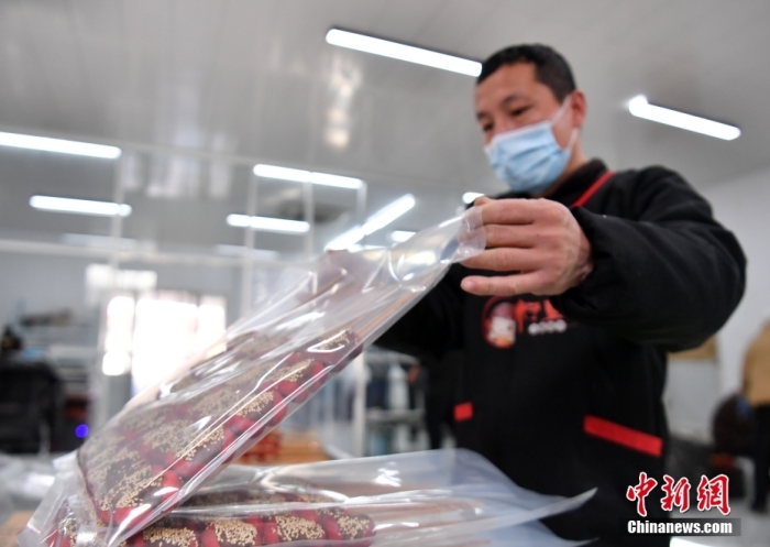 1月18日，雄安新區(qū)大樹劉莊村辛愛青家中的冰糖葫蘆加工廠，工人正對冰糖葫蘆半成品進行真空塑封。作為遠近聞名的“冰糖葫蘆村”，大樹劉莊村制作冰糖葫蘆的歷史已有100多年，全村三分之二的村民都會這門手藝，吸引不少游客慕名而來。 中新社記者 韓冰 攝